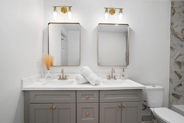 bathroom with toilet, a sink, and double vanity