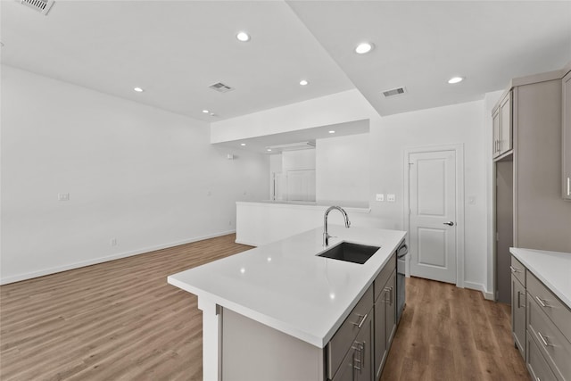 kitchen featuring light wood-style flooring, a sink, visible vents, gray cabinetry, and light countertops