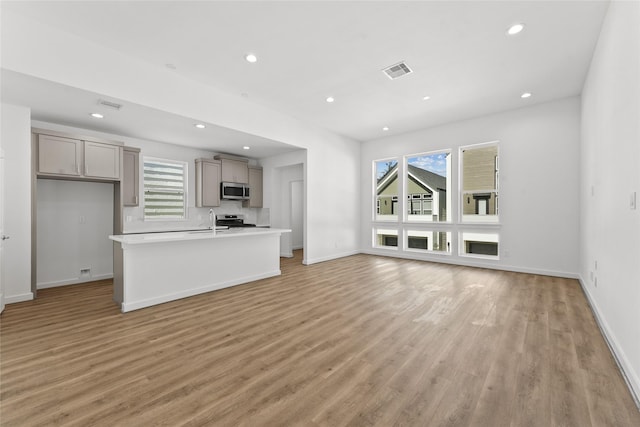 unfurnished living room with recessed lighting, plenty of natural light, visible vents, and light wood-style flooring