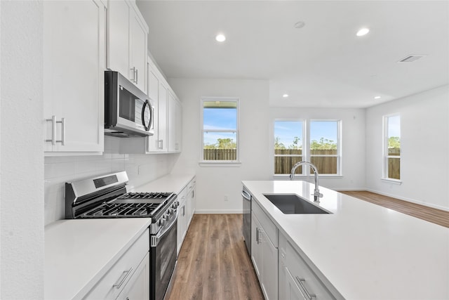 kitchen with recessed lighting, light wood-style flooring, stainless steel appliances, and a sink