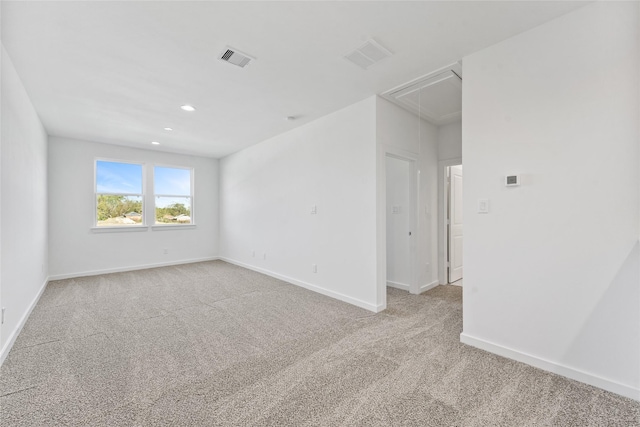 empty room featuring attic access, light carpet, baseboards, visible vents, and recessed lighting