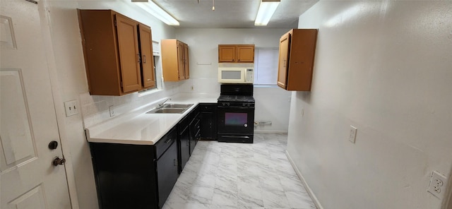 kitchen with a sink, brown cabinets, white microwave, light countertops, and black gas range oven