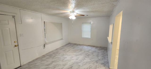 spare room with a ceiling fan, baseboards, and a textured ceiling