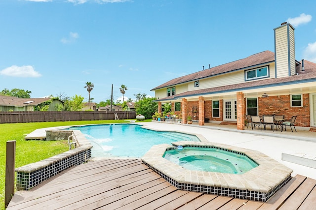 view of swimming pool with a fenced backyard, a wooden deck, a patio area, a lawn, and a pool with connected hot tub