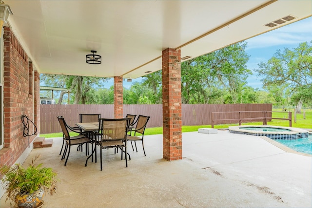 view of patio / terrace featuring a fenced backyard, outdoor dining area, visible vents, and an in ground hot tub