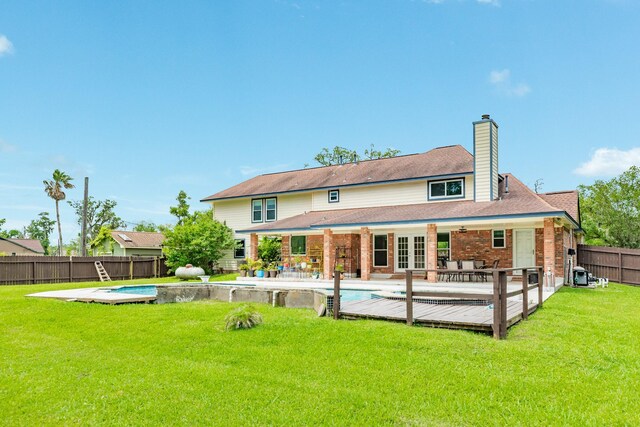 rear view of property featuring a fenced in pool, a fenced backyard, a chimney, a patio area, and a yard