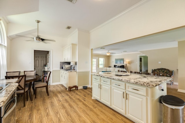 kitchen with crown molding, light wood-style flooring, a ceiling fan, and open floor plan