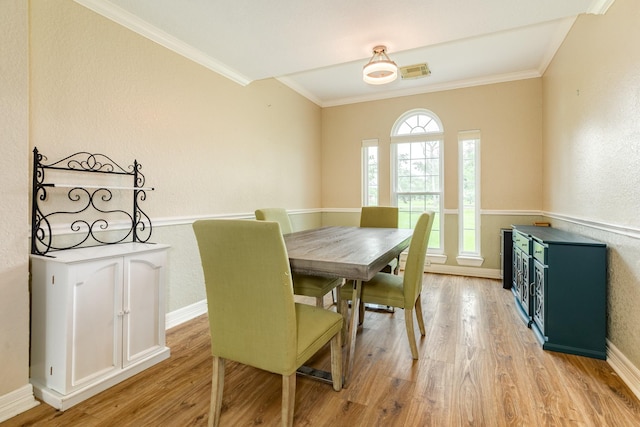 dining space with light wood-type flooring, baseboards, visible vents, and crown molding