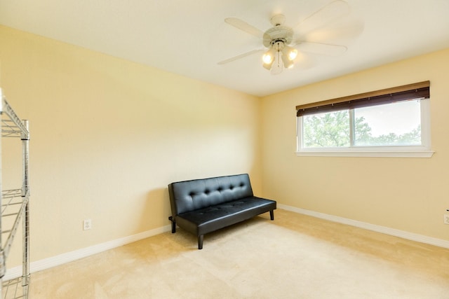 living area featuring carpet, a ceiling fan, and baseboards