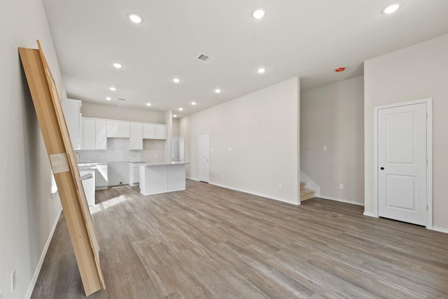 8685 Sassafras St, Willis, TX 77318 - unfurnished living room featuring baseboards, visible vents, recessed lighting, light wood-style floors, and stairway