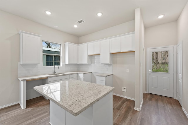 8685 Sassafras St, Willis, TX 77318 - kitchen with tasteful backsplash, a sink, white cabinets, visible vents, and a kitchen island