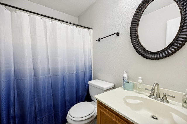bathroom featuring a textured wall, toilet, and vanity