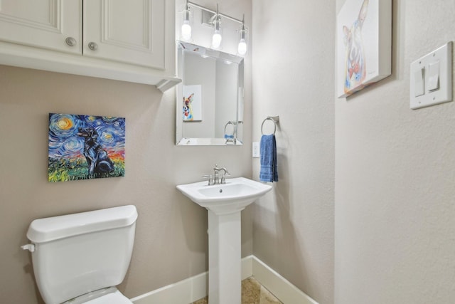 bathroom featuring baseboards, a sink, and toilet