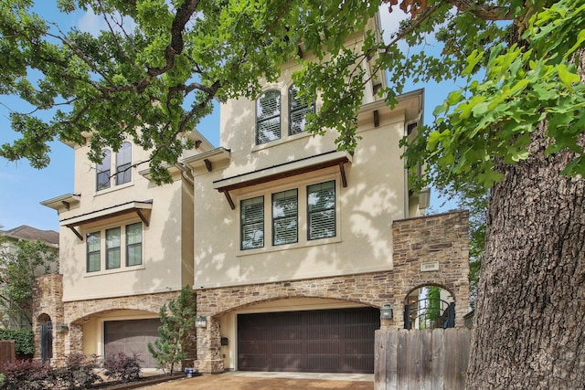 view of front facade featuring an attached garage, stone siding, stucco siding, and fence