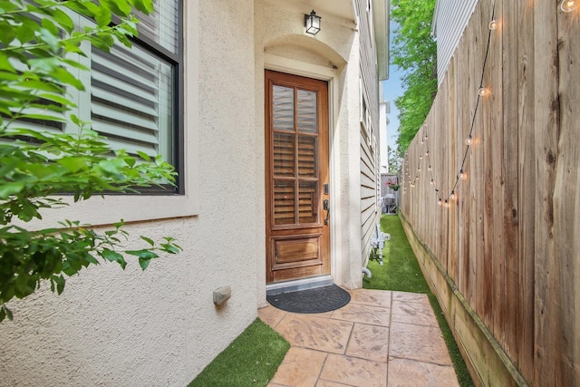 property entrance with fence and stucco siding