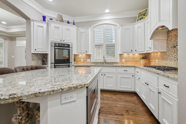 kitchen with white cabinets, crown molding, stainless steel appliances, and a sink