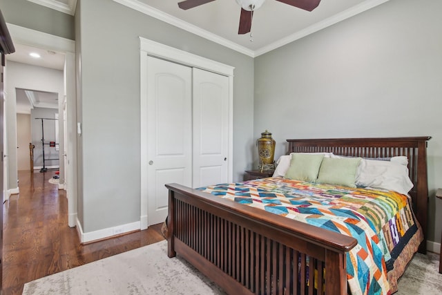 bedroom featuring wood finished floors, baseboards, a closet, and crown molding