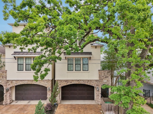 view of front of house with stucco siding, driveway, an attached garage, and stone siding