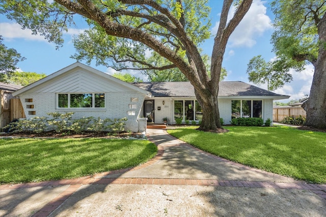 ranch-style house with brick siding, a front yard, and fence