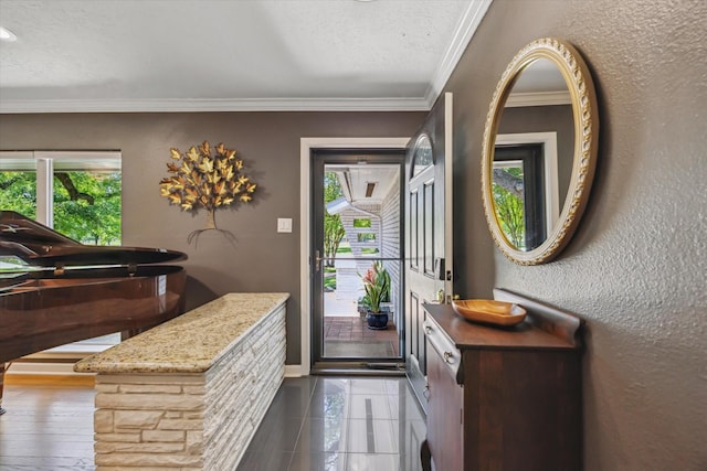 entryway with a textured ceiling, a wealth of natural light, baseboards, and ornamental molding
