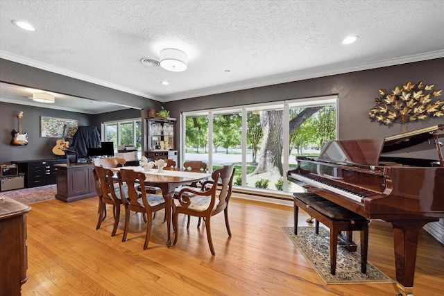 dining room featuring light wood finished floors, a textured ceiling, recessed lighting, and ornamental molding