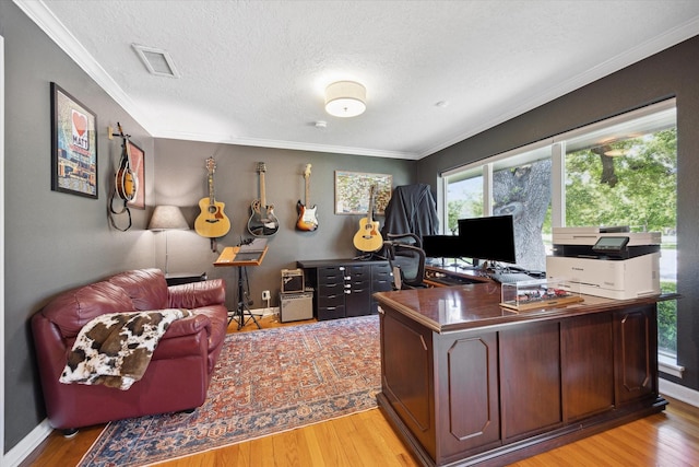 office with a textured ceiling, baseboards, visible vents, light wood-style floors, and crown molding