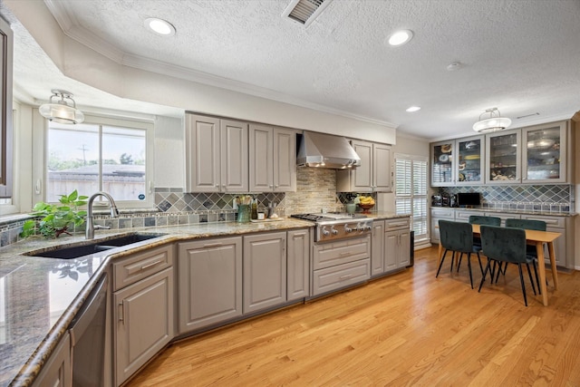 kitchen featuring light wood-style flooring, wall chimney exhaust hood, crown molding, and a sink
