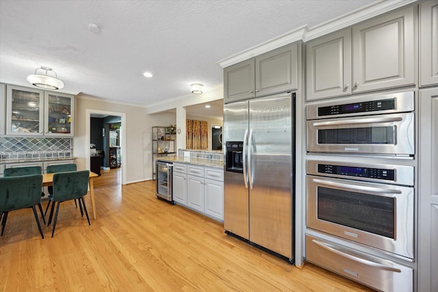 kitchen featuring decorative backsplash, beverage cooler, a warming drawer, gray cabinets, and stainless steel appliances
