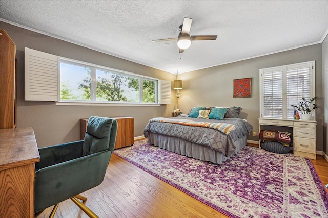bedroom featuring wood finished floors, a textured ceiling, baseboards, and ceiling fan