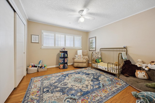bedroom featuring crown molding, wood finished floors, a textured ceiling, and a closet