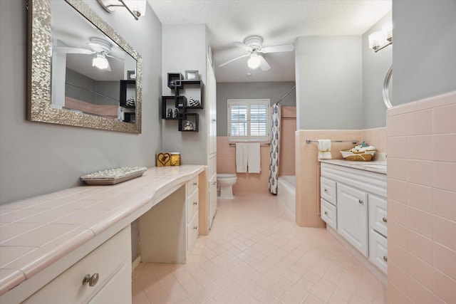 full bath with tile walls, a ceiling fan, vanity, and toilet