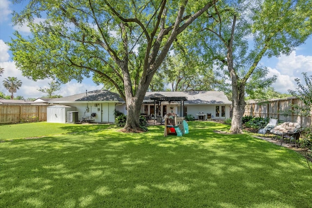back of house featuring a pergola, a fenced backyard, an outbuilding, a lawn, and a storage unit