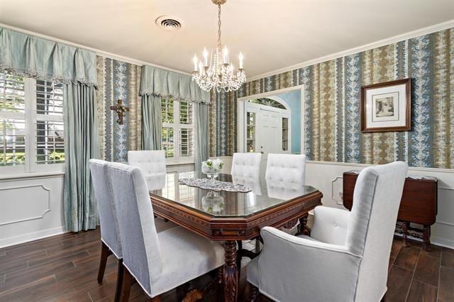 dining area with a chandelier, wallpapered walls, wood finished floors, and visible vents