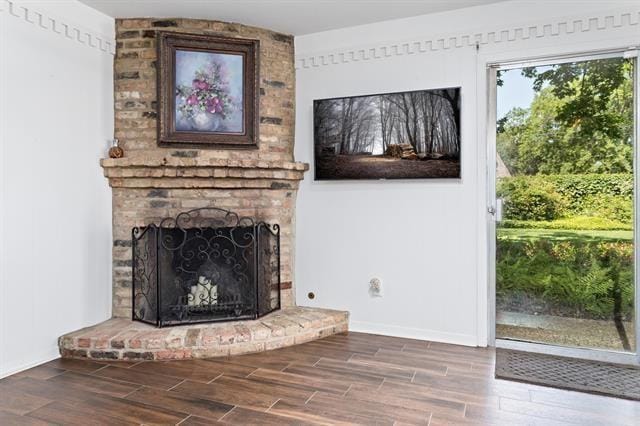 unfurnished living room with baseboards, wood finished floors, and a fireplace