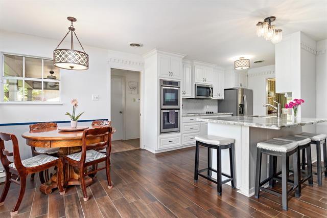 kitchen with stainless steel appliances, a peninsula, a sink, dark wood-style flooring, and a breakfast bar