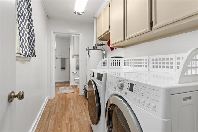 laundry room featuring washing machine and dryer, light wood-style flooring, cabinet space, and baseboards