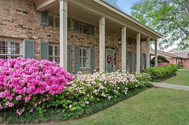 view of home's exterior featuring brick siding, a yard, and covered porch