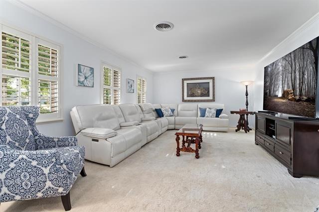 living area featuring light carpet, ornamental molding, and visible vents