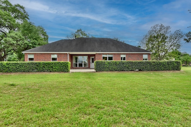 rear view of house with brick siding and a lawn