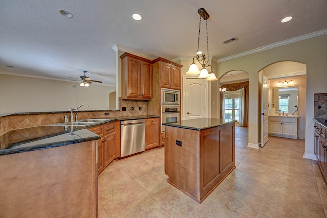 kitchen featuring stainless steel appliances, a sink, arched walkways, a kitchen island, and ceiling fan with notable chandelier
