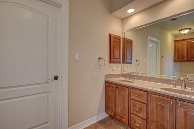 bathroom featuring double vanity, tile patterned flooring, baseboards, and a sink