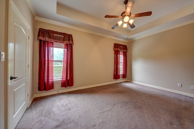 carpeted spare room featuring baseboards, a ceiling fan, a tray ceiling, and ornamental molding