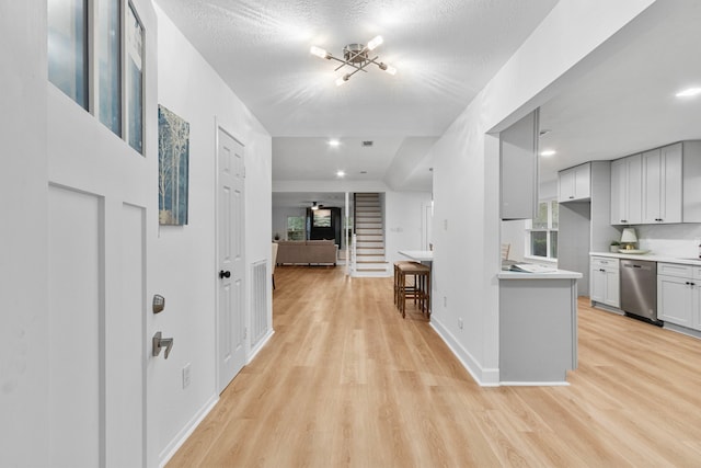 interior space featuring light countertops, dishwasher, light wood-style floors, baseboards, and open floor plan