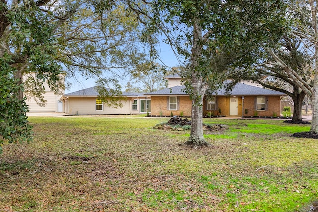 back of property with a yard, a shingled roof, and a garage