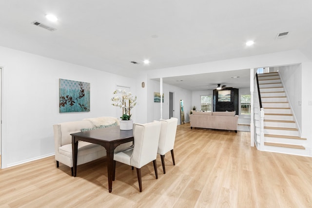 dining space featuring light wood-type flooring, visible vents, and stairway