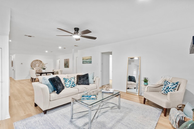 living area with light wood-style floors, visible vents, and ceiling fan
