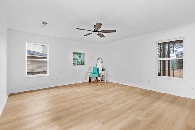 empty room featuring baseboards, visible vents, light wood-style floors, and ceiling fan