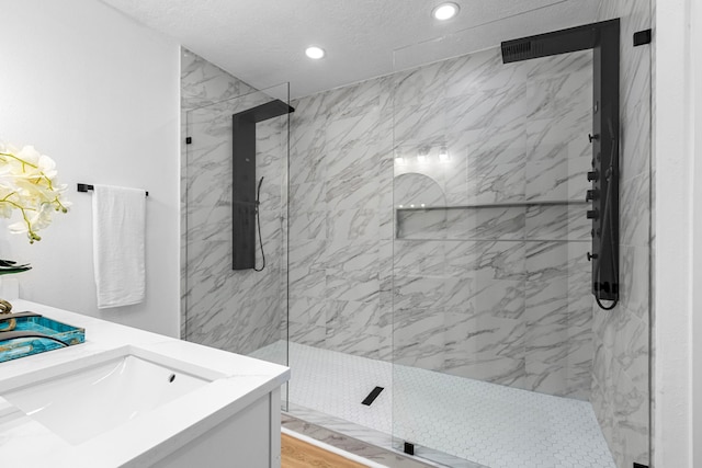 full bathroom featuring a marble finish shower, recessed lighting, and a sink