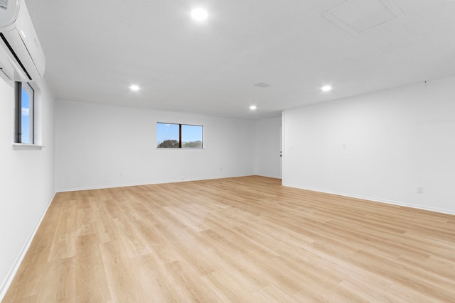 unfurnished room with recessed lighting, a wall mounted air conditioner, baseboards, and light wood-type flooring