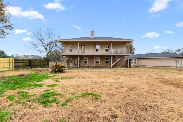 back of house featuring stairway, a chimney, a lawn, a deck, and a fenced backyard